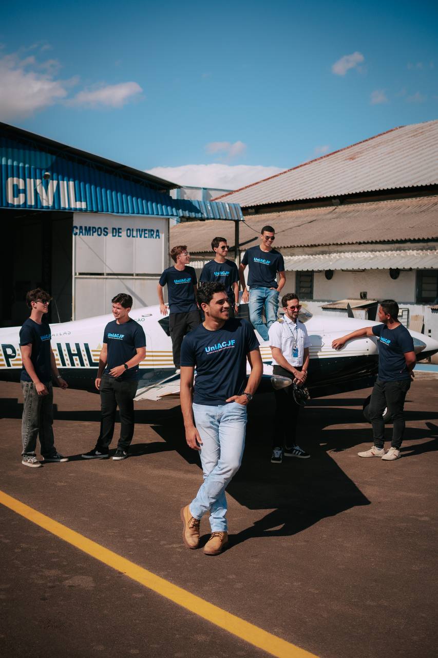 Alunos posando ao redor de uma aeronave no pátio